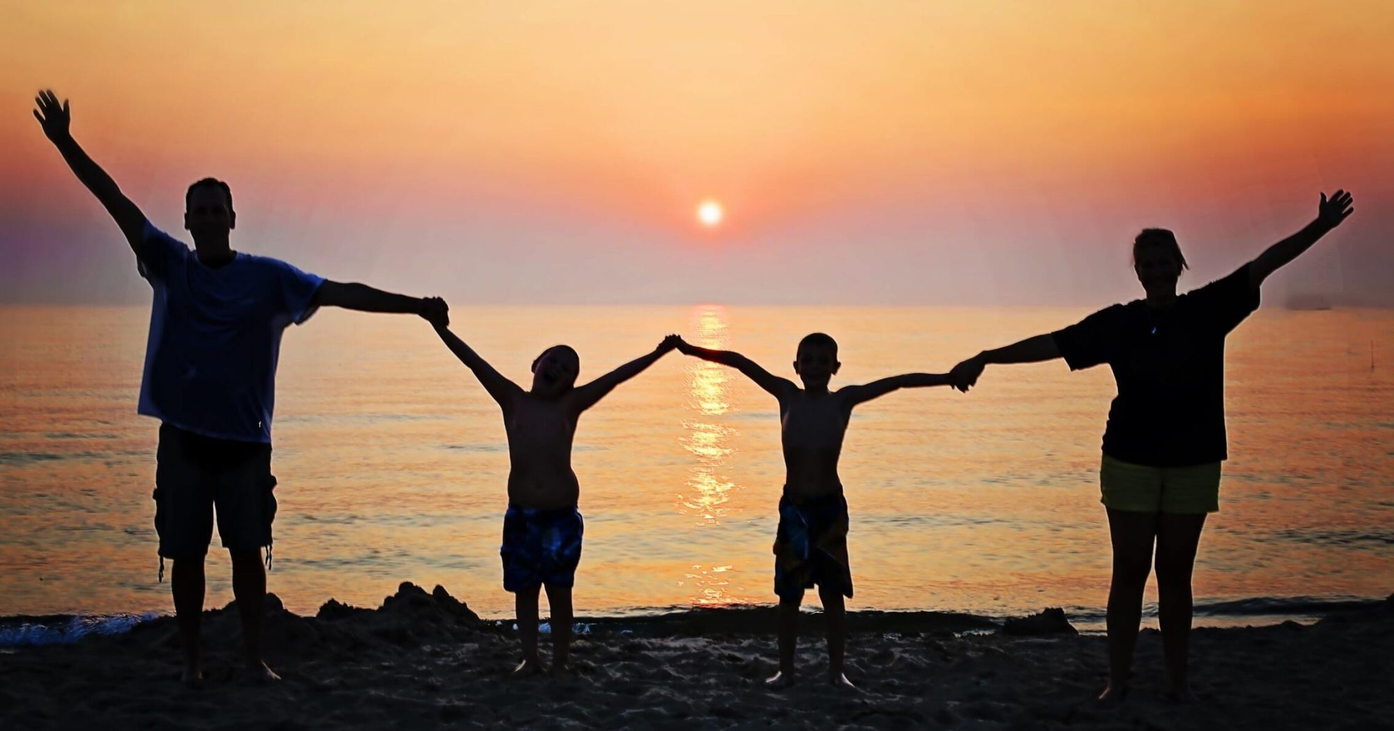 Happy family holding hands at sunset on the beach – Eleven Legal trusted legal advice