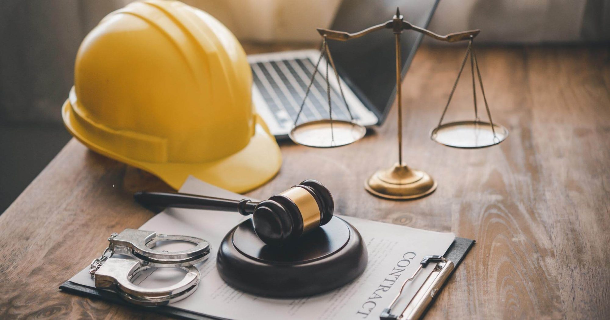 Yellow hard hat, gavel, and scales of justice on a desk – Eleven Legal strata and construction law