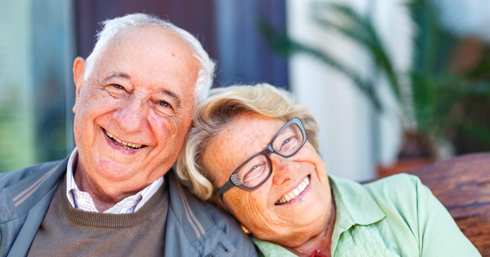 Smiling elderly couple sitting outdoors – Eleven Legal power of attorney services