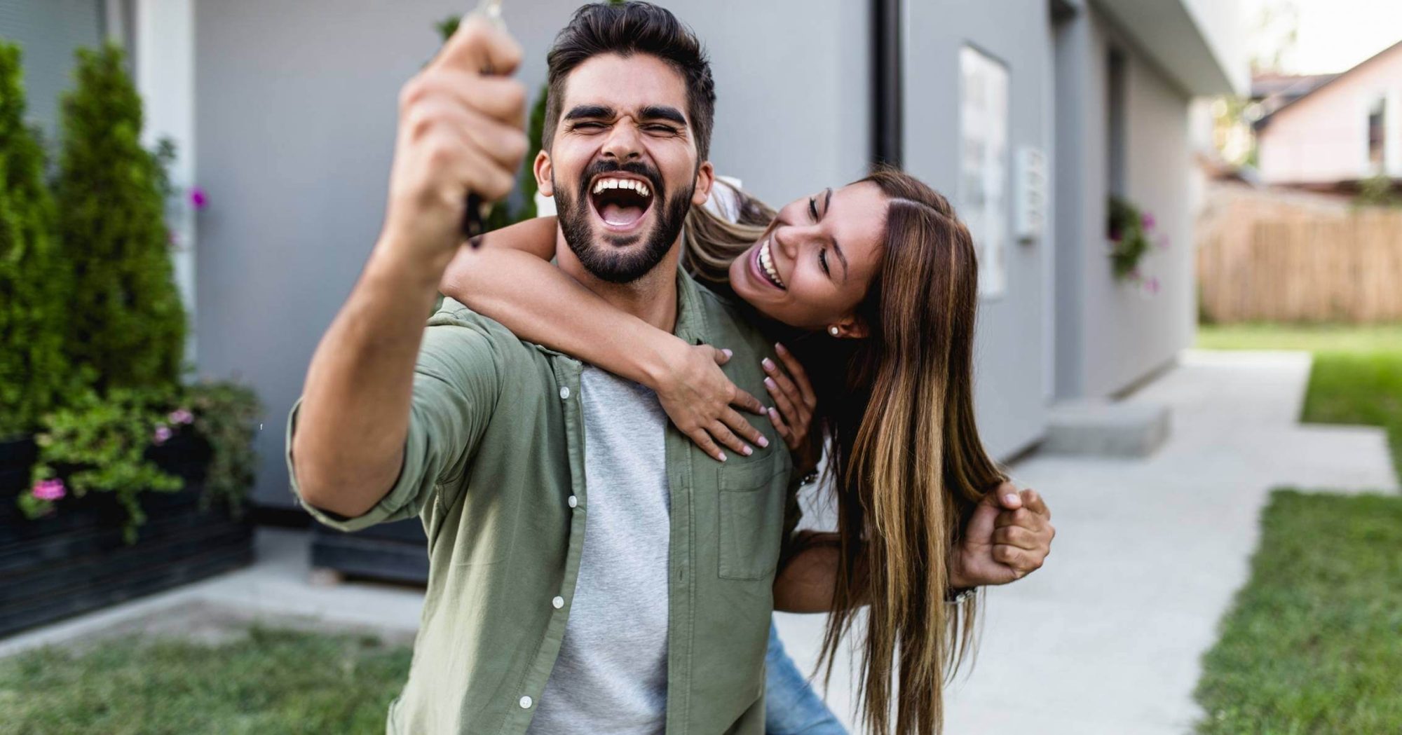 Happy couple holding house keys in front of their new home – Eleven Legal home purchase services