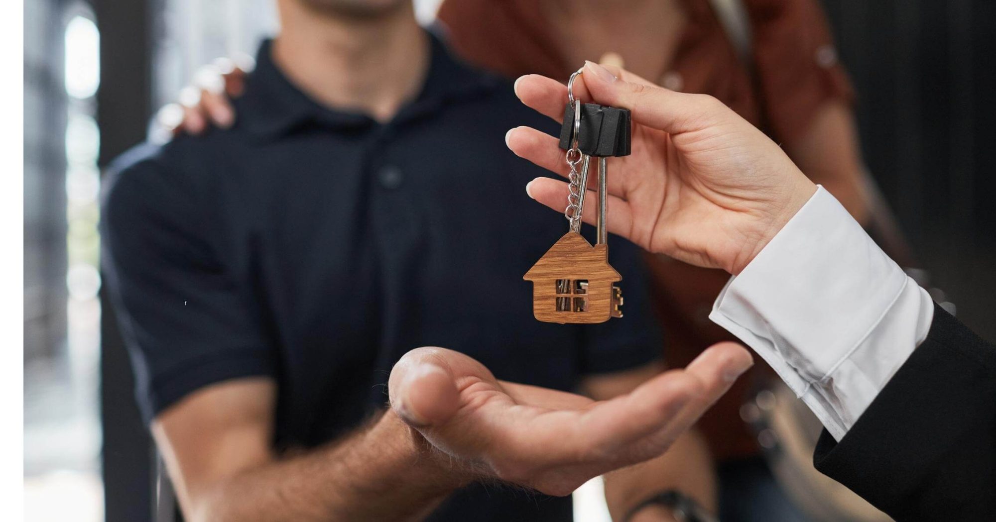 Person handing over house keys to a couple – Eleven Legal real estate and conveyancing services